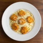 Top-down view of crispy garlic chicken over creamy parmesan linguine